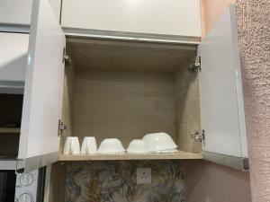 a cupboard with some white dishes in it at StayVerse74 in Noida