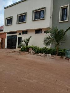 a building with two palm trees in front of it at Studio Lac Rose in Abomey-Calavi