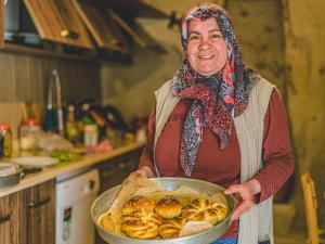 a woman holding a pan of food in a kitchen at Atilla's Cave Hotel in Nevşehir