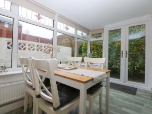 a dining room with a table and chairs and windows at Pebbles Reach in Colwyn Bay