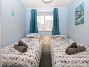 two beds in a bedroom with blue walls and blue curtains at Pebbles Reach in Colwyn Bay