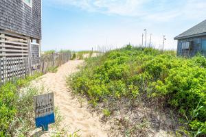 a sign on a sandy beach next to a fence at Sea Sun Greetings - Kitty Hawk MP 2.5, Ocean Views, Direct Beach Access, Pool, Hot Tub, Pets OK in Kitty Hawk