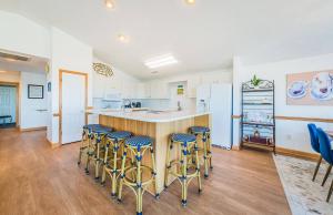 a kitchen with a island with bar stools at Sea Sun Greetings - Kitty Hawk MP 2.5, Ocean Views, Direct Beach Access, Pool, Hot Tub, Pets OK in Kitty Hawk