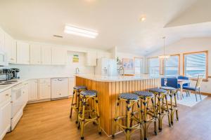 a kitchen with white cabinets and a bar with stools at Sea Sun Greetings - Kitty Hawk MP 2.5, Ocean Views, Direct Beach Access, Pool, Hot Tub, Pets OK in Kitty Hawk