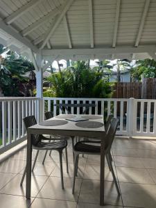 a table and chairs on a patio with a white pergola at La petite kaz in Saint-François