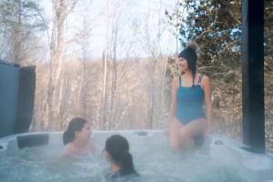 two girls sitting in a jacuzzi tub in a forest at Le Yéti de Tremblant in La Conception