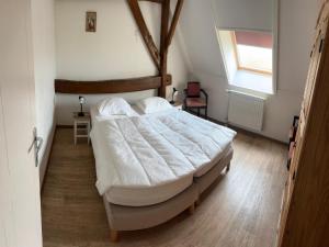 a bedroom with a large white bed with a window at Farmhouse home in Eede in Eede