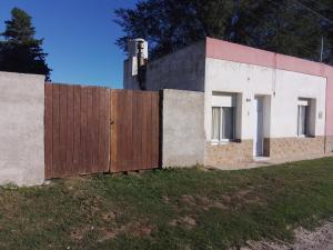 a house with a wooden fence in a field at La casita in Pringles