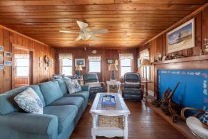 a living room with a blue couch and a ceiling fan at Mitch's Haven - Kitty Hawk MP 2, Oceanfront, 3 Bedrooms, Vintage Charming Cottage in Kitty Hawk