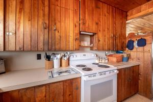 a kitchen with a white stove and wooden cabinets at Mitch's Haven - Kitty Hawk MP 2, Oceanfront, 3 Bedrooms, Vintage Charming Cottage in Kitty Hawk +42 photos