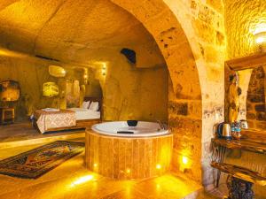 a bedroom with a bed and a tub in a room at Atilla's Cave Hotel in Nevşehir
