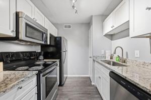 a kitchen with black appliances and white cabinets at Bright two-bed wupgraded fixtures in Denton