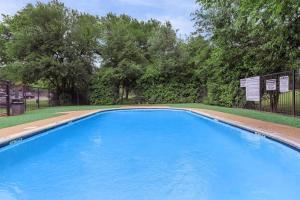 a large blue swimming pool with trees in the background at 2-bedroom with large living area in Denton