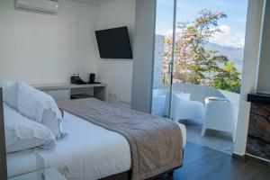 a bedroom with a bed and a balcony with a television at Hotel PAUCHÉ Topiario Zapatoca in Zapatoca +73 photos