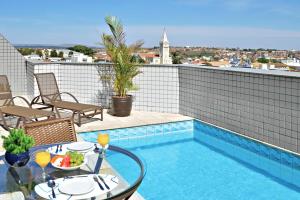 a patio with a table and a swimming pool at Plaza Inn Flat Araxá in Araxá