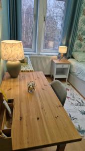 a wooden table in a living room with a lamp and two windows at Le Nichoir de la Biesme in Aiseau