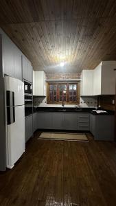 a kitchen with white appliances and a wooden ceiling at Casa com vista para a natureza e piscina in Garopaba