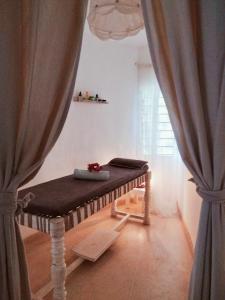 a bed sitting in a room with curtains at Lady D House Watamu in Watamu