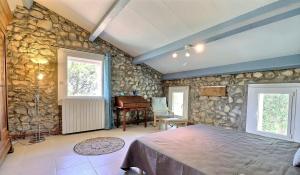 a bedroom with a stone wall with a bed and a piano at La Rochere in Sampzon +17 photos