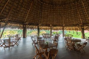a restaurant with tables and chairs and a thatched roof at Hotel Casa Encanto in Doradal