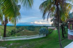 a house with a white fence and palm trees at Hotel Casa Encanto in Doradal