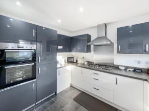 a kitchen with white cabinets and black appliances at Modern spacious Home in Rhyl in Rhyl