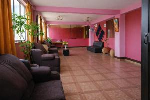 a waiting room with couches and chairs and pink walls at Hospedaje Tikari in Chincheros