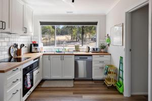 a kitchen with white cabinets and a sink and a window at Nanda Lake House in Bonnie Doon