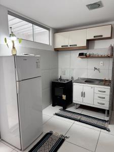 a kitchen with white cabinets and a refrigerator at Margem do São Francisco 104 praiano in Petrolina