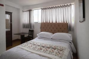 a bedroom with a bed and a table and a window at Hospedaje Tikari in Chincheros