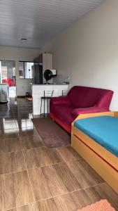 a bedroom with a red bed and a kitchen at Casa privativa Próximo a Itaipu in Foz do Iguaçu