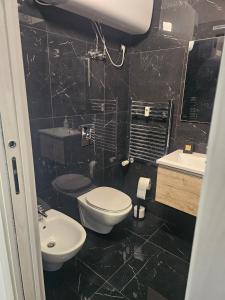 a black tiled bathroom with a toilet and a sink at BENNY'S MOUNTAIN b&b in Pescocostanzo
