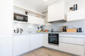 a white kitchen with white cabinets and appliances at Little Dream Apartment Sitges in Sitges