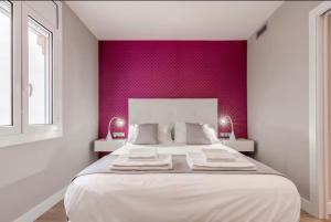 a bedroom with a large white bed with a red wall at Little Dream Apartment Sitges in Sitges