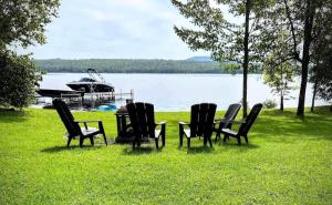 four chairs and a table in the grass near a lake at Chalet Le Shack O2 in Stratford