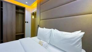a bedroom with a white bed with white pillows at Bayford Suites in Abuja