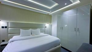 a bedroom with a white bed and a blue chair at Bayford Suites in Abuja +20 photos