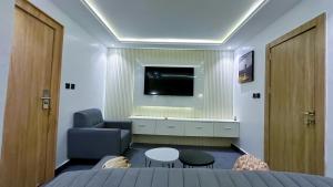 a bedroom with a bed and a tv on a wall at Bayford Suites in Abuja