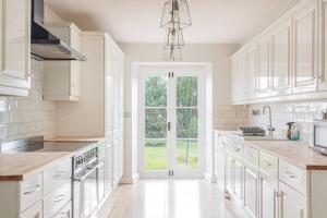 a kitchen with white cabinets and a large window at Washmere House in Colerne