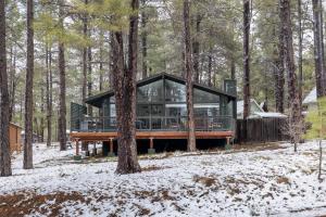 a glass house in the woods in the snow at Pine Cone Cabin Flagstaff 3BR 2BA in Flagstaff