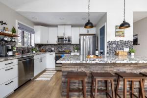 a kitchen with white cabinets and a counter with stools at Pine Cone Cabin Flagstaff 3BR 2BA in Flagstaff