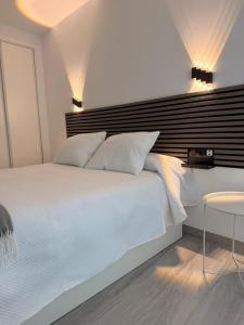 a bedroom with a white bed with a black headboard at Apartamento Las Cruces in Plasencia