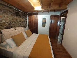 a large bed in a room with a stone wall at Casa Nayala in Río Aller