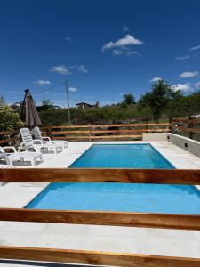 a swimming pool with chairs and a table at L&M Cabañas Villa Yacanto in Villa Yacanto