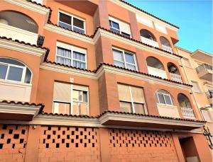 a large orange building with windows and balconies at Estudio a 5 minutos del Aeropuerto in Torrellano