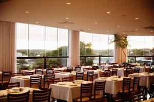 a dining room with tables and chairs and large windows at Gálatas Golden Hotel in Patos de Minas