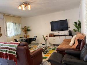 a living room with a couch and a flat screen tv at Villa Golden Gâte 8 Bred room in Dombé