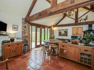 a kitchen with wooden cabinets and a table with stools at Corn House in Plaish