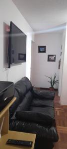 a black leather couch in a living room with a flat screen tv at Frente al mar in Montevideo