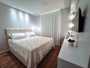 a bedroom with a white bed and a television at Apartamento com 2 quartos a 5 minutos do centro in Brusque